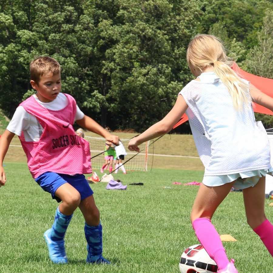 Two campers go one-on-one for the ball on the grass